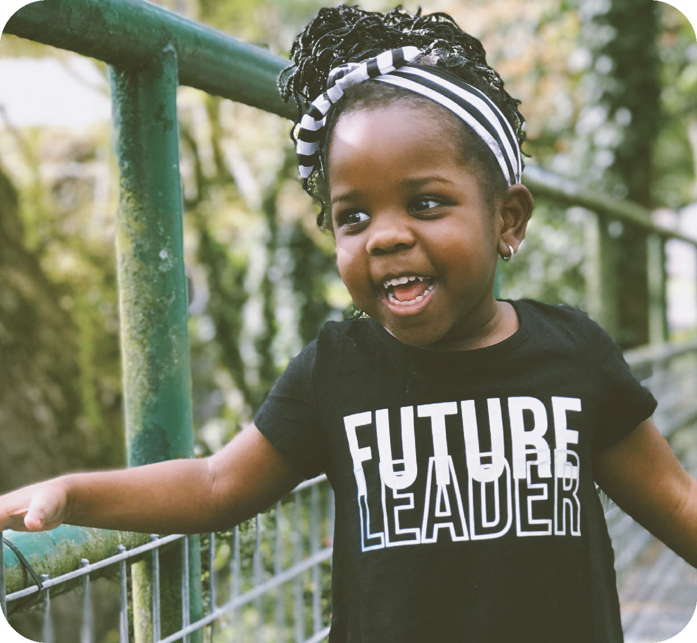 Close up of child smiling on bridge with shirt with text that says Future Leader